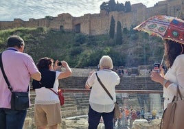 Turistas inmortalizan su paso por el Centro de Málaga, con la estampa de la Alcazaba al fondo.