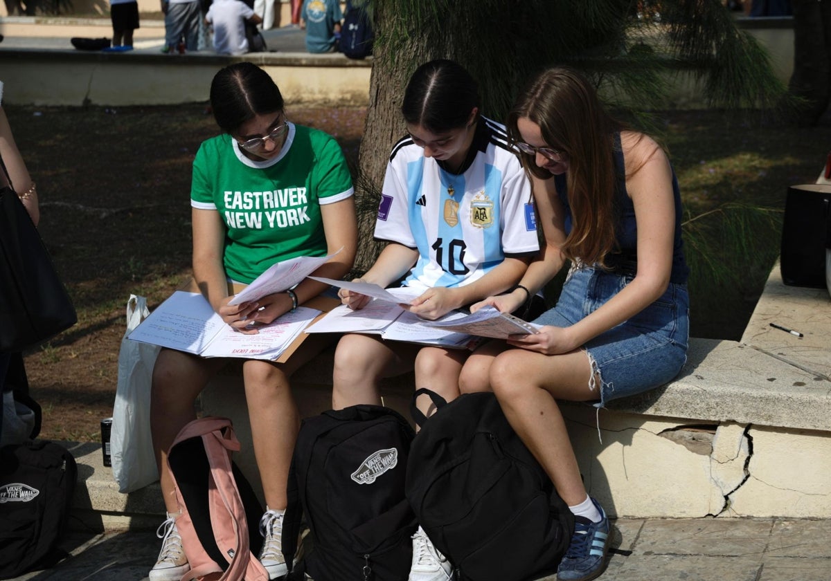 Tres jóvenes repasan antes de hacer uno de los exámenes de la selectividad, en Málaga.