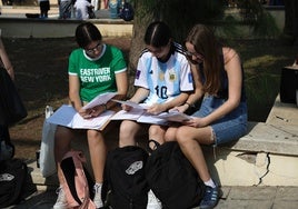 Tres jóvenes repasan antes de hacer uno de los exámenes de la selectividad, en Málaga.