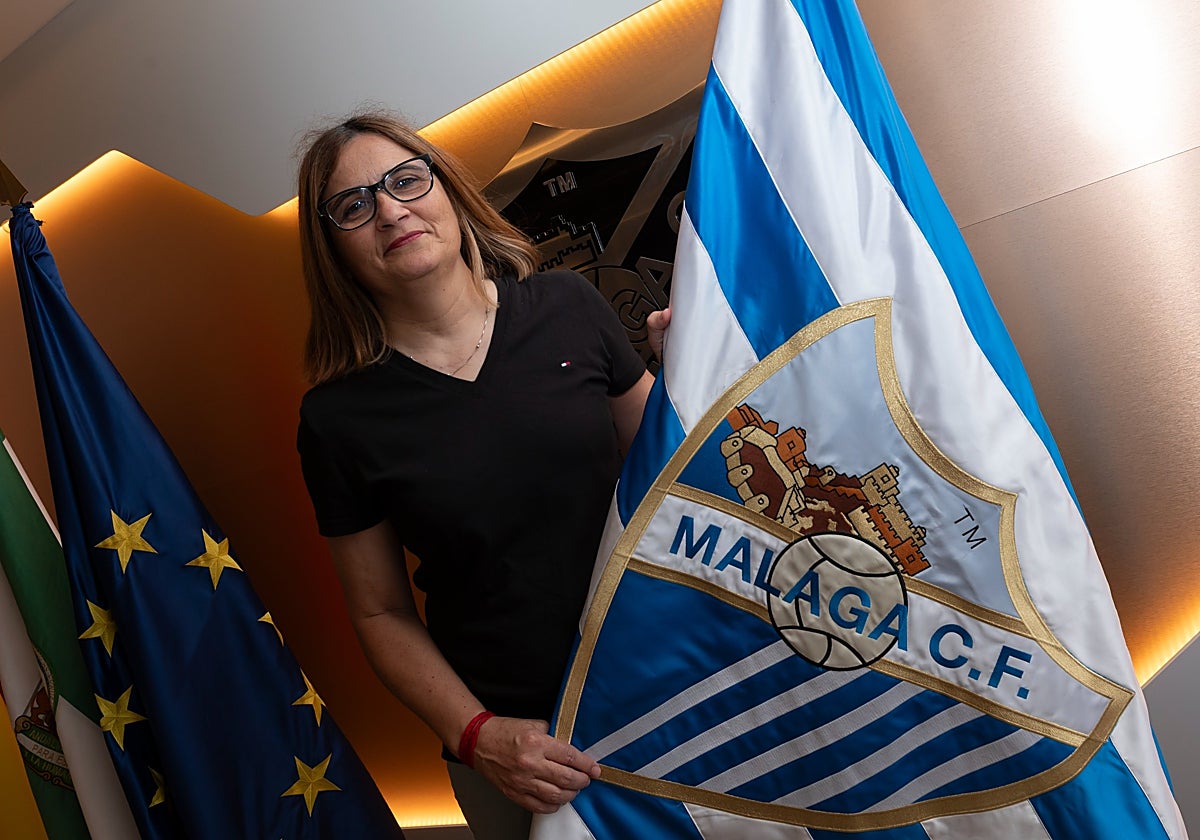 Estrella Díaz posa con una bandera del Málaga tras hacerse oficial que será la nueva directora deportiva de la sección femenina.