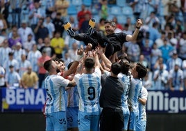 Los jugadores del Atlético Malagueño mantean a su entrenador, Funes, tras consumarse en La Rosaleda el ascenso a Segunda RFEF.