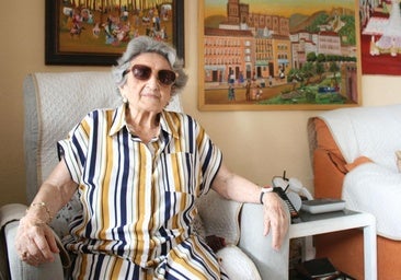 Trinidad posa en el salón de su casa, presidido por tres de los cuadros que realizó después de haber empezado a pintar con 70 años.