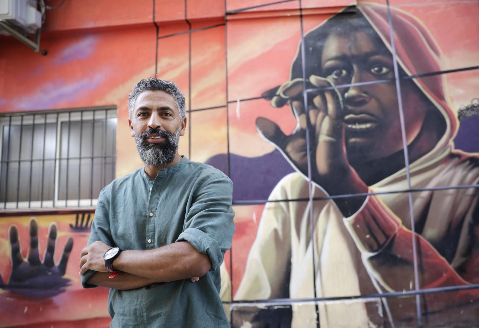 Ahmed Khalifa posa ante uno de los murales que luce la fachada del local que la asociación que preside tiene en Málaga.