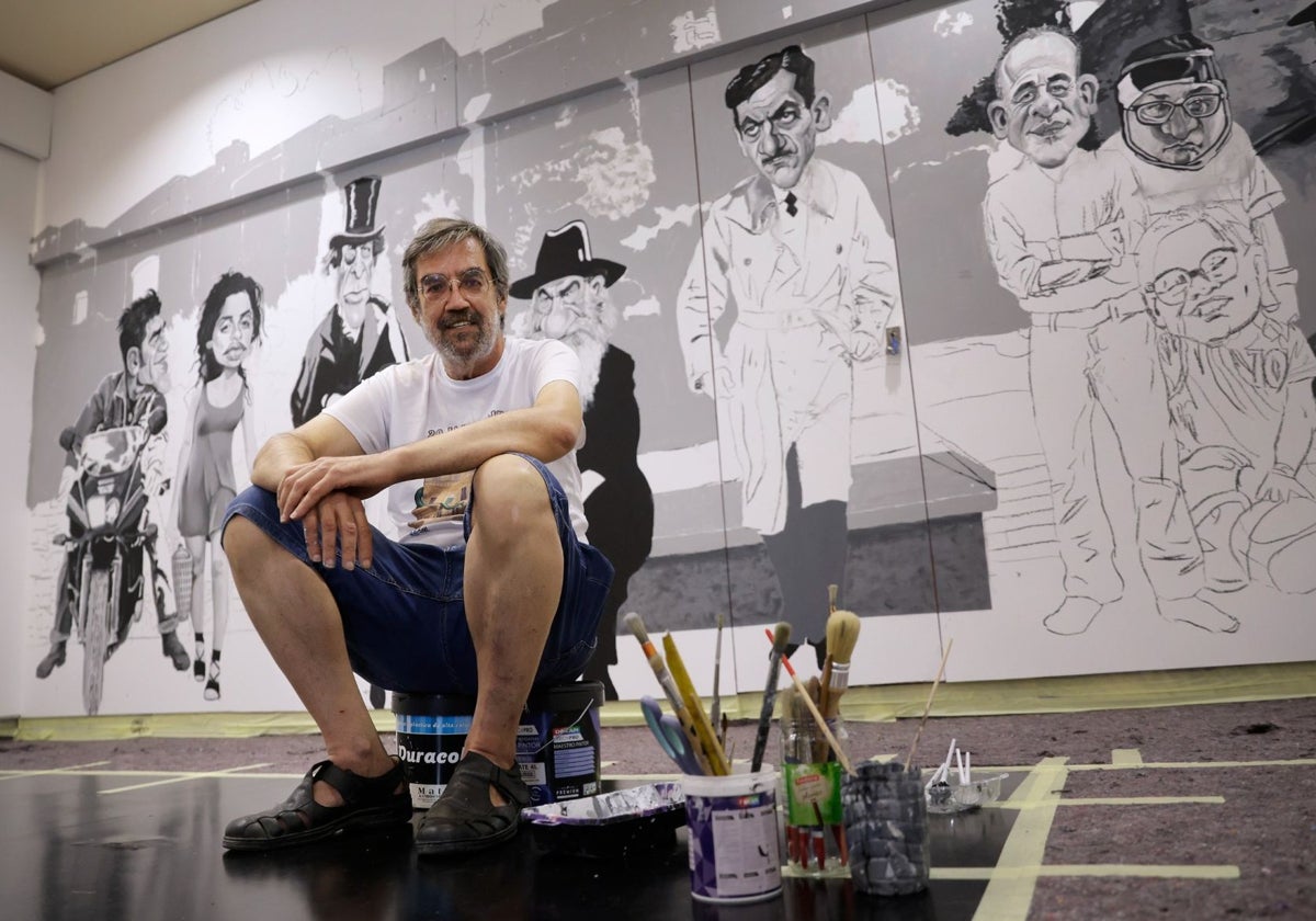 Ángel Idígoras, sentado sobre los botes de pintura, con los primeros personajes de su nuevo mural cinéfilo.