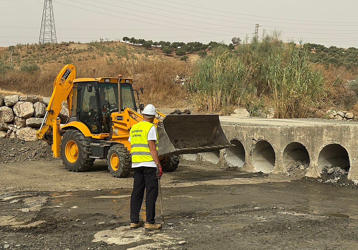 Una máquina retroexcavadora y el alcalde de Cártama, Jorge Gallardo en la zona de desatoro en los conductos del paso del arroyo Torre con el arroyo Gorrino.
