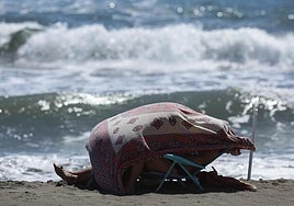 Imagen de un bañista protegiéndose del viento, este jueves en Rincón de la Victoria