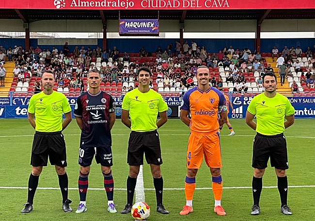Los capitanes del Extremadura (Salva Sevilla) y el Malagueño (Recio), con el trío arbitral.