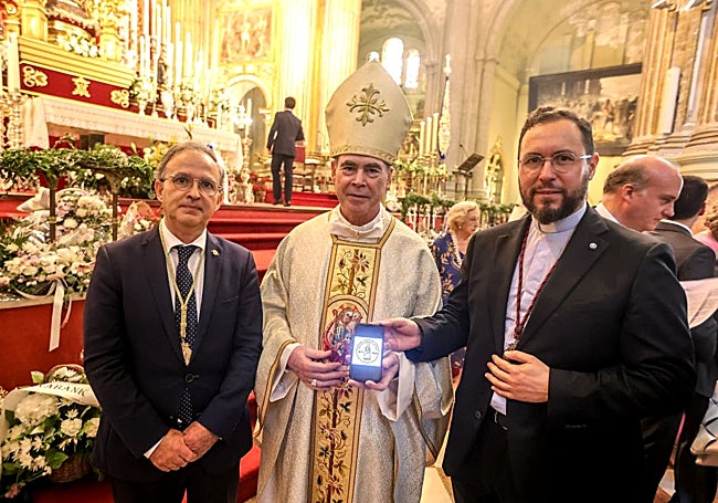 El obispo administrador apostólico de Málaga, Jesús Catalá, muestra el matasellos vaticano, junto al sacerdote rondeño Oficial de la Santa Sede, Salvador Aguilera, acompañados por el hermano mayor de la Hermandad de la Victoria, Miguel Orellana.
