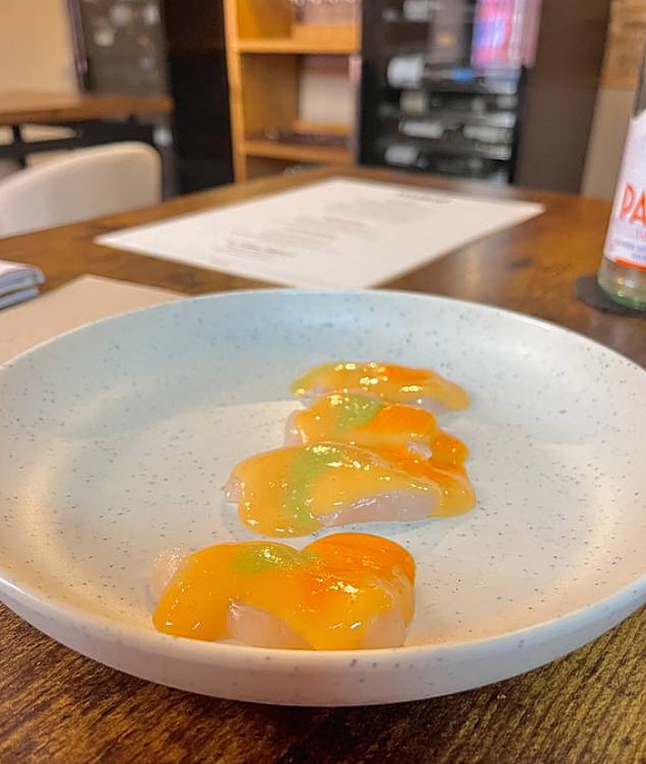 Imagen secundaria 2 - Arriba, el sumiller junto a una muestra de algunas de sus botellas. Abajo, tartar de atún con gazpachuelo y vieira con gazpacho de naranja. 