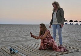 De pie, Lola de la Oliva, junto a Beatriz Liaño, que hace una fotografía a uno de sus modelos en una playa de Marbella.