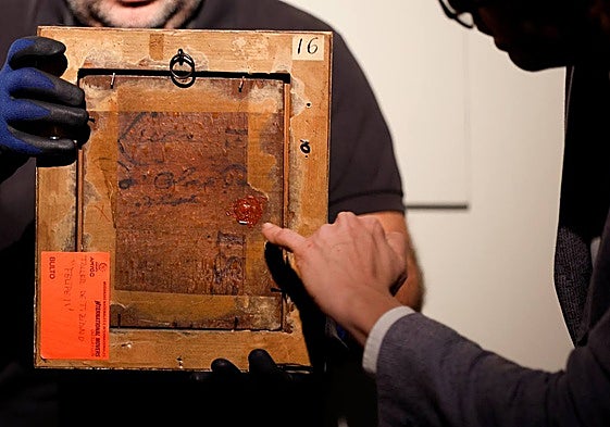 El comisario señala el sello lacrado de la familia real británica en el reverso del óleo de Felipe II.