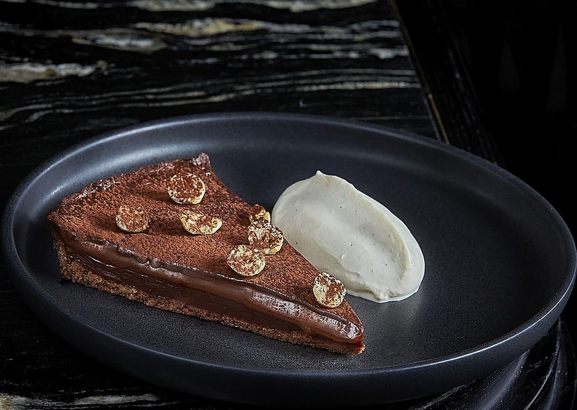 Imagen principal - Leña: uno de los imprescindibles del restaurante marbellí es esta tarta de chocolate cremosa con avellanas tostadas. El Alimentario: en su carta de postres, el restaurante de Torre del Mar incluye desde la clásica tarta de limón hasta un arroz con leche con piña al curry y helado de coco. Areia: Soufflé Grand Marnier 'à la minute' que se termina en mesa flambeándolo con licor de naranja.