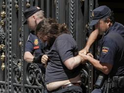 Dos agentes desalojan a uno de los manifestantes en el Casino de Madrid. / Efe