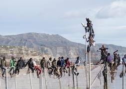 Inmigrantes encaramados en la parte alta de la valla de Melilla. / Foto: Blasco de Avellaneda | Vídeo: Atlas