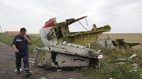 Un miembro de los servicios de rescate, junto a restos del vuelo MH 17.