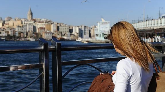 Mujer mira su teléfono frente a la mezquita de Suleymaniye, en Estambul.