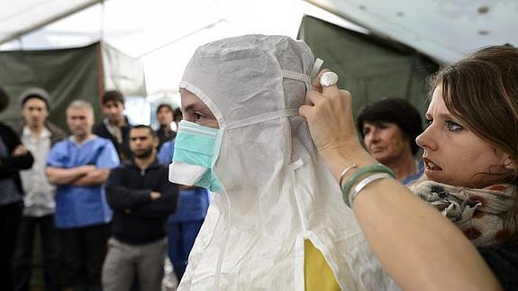 Un sanitario se coloca el traje de protección. 