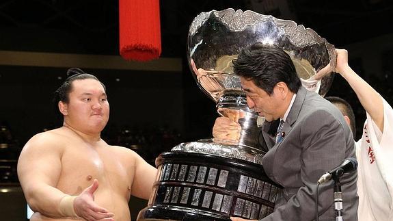 Shinzo Abe le entrega a Hakuho uno de sus 31 trofeos.