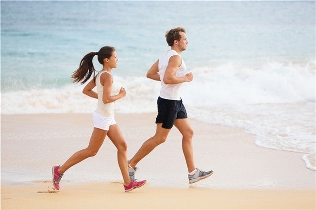 Una pareja corre por la arena de la playa 