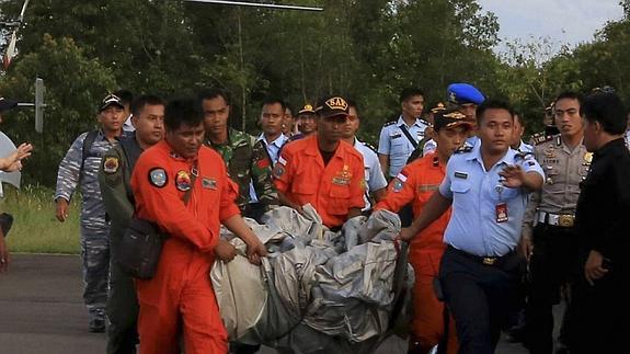 Los equipos de rescate trasladan un cadáver. 