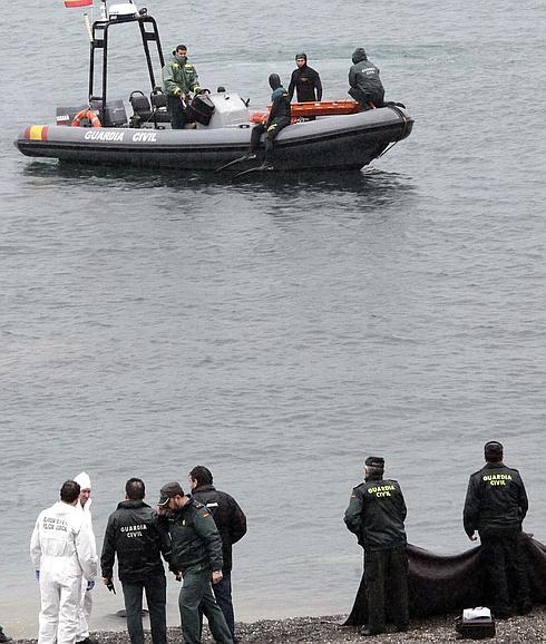 Varios agentes custodian el cuerpo de un inmigrante en El Tarajal. 