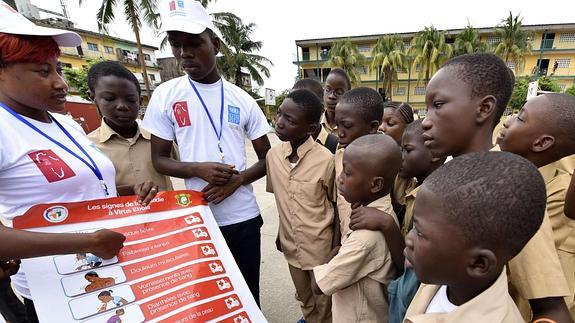 Voluntarios muestran a los niños de Costa de Marfil una pancarta en la que se explican los síntomas del virus del ébola. 