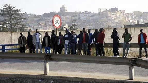 Inmigrantes en la carretera de acceso al paso fronterizo, situada junto al CETI. 