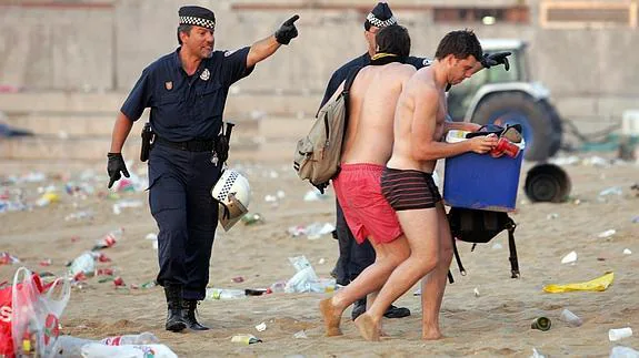 Una patrulla de la Guardia Urbana desaloja a jóvenes de una playa.