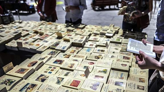 Varias personas miran un puesto de libros en el mayor salón de lectura al aire libre de Madrid -en la Plaza Sánchez Bustillo, junto al Museo Reina Sofía.