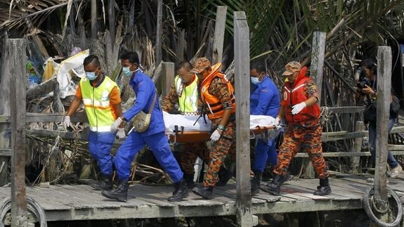 Miembros de un equipo de rescate malasio recuperan un cadáver. 