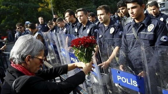 Una mujer muestra unas flores a los policías. 