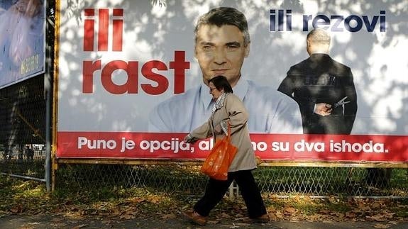 Una mujer pasea junto a una pancarta electoral del Partido Socialdemócrata en el centro de Zagreb (Croacia). 