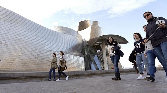 Varias personas pasean en la inmediaciones del museo Guggenheim en Bilbao.