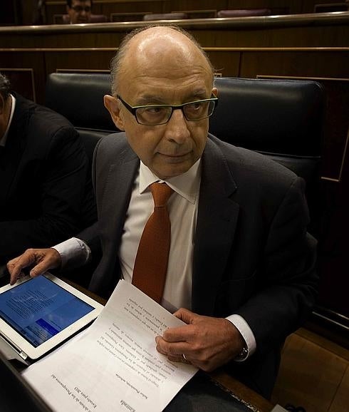 Cristóbal Montoro consulta una tableta en su escaño. 