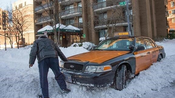 Una taxista trata de sacar su vehículo de la nieve.