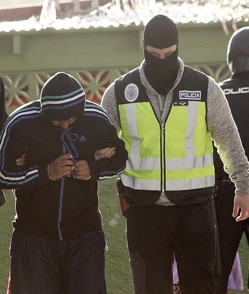 Un policía conduce a uno de los detenidos.