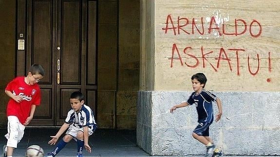 Un grupo de niños juega junto a una pintada a favor de Otegi. 