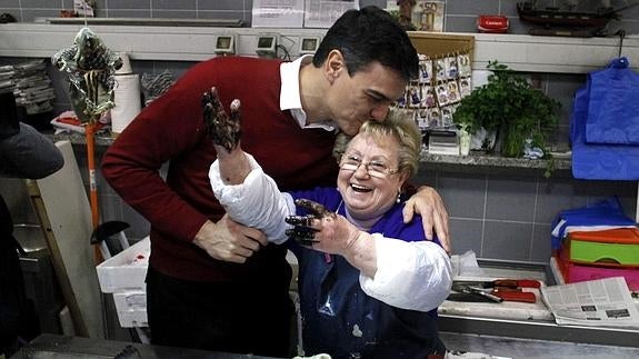 El secretario general del PSOE, Pedro Sánchez, conversa con trabajadores del mercado de la Plaza de Lugo, en La Coruña.