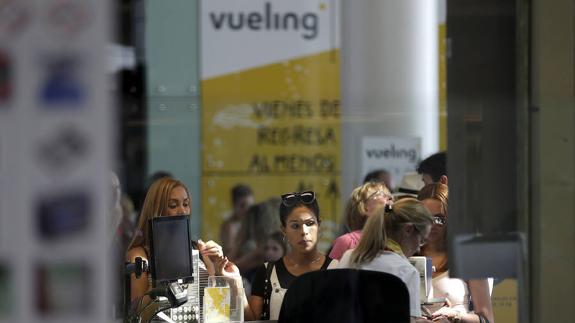 Personal de facturación de Vueling atiende a los viajeros en el Aeropuerto de El Prat.