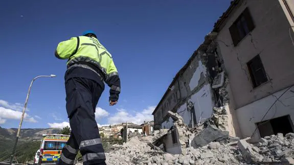 Un efectivo de los servicios de emergencia pasa ante los escombros de un edificio derrumbado en Accumoli.