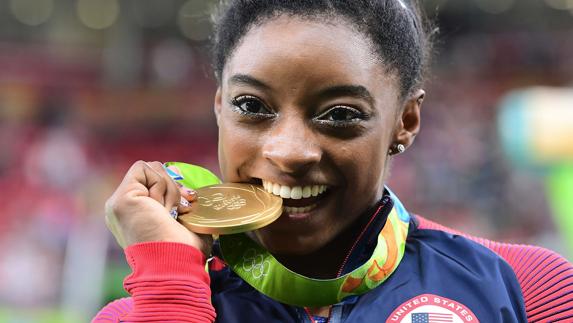 La gimnasta estadounidense Simone Biles muerde una medalla de oro olìmpica. 
