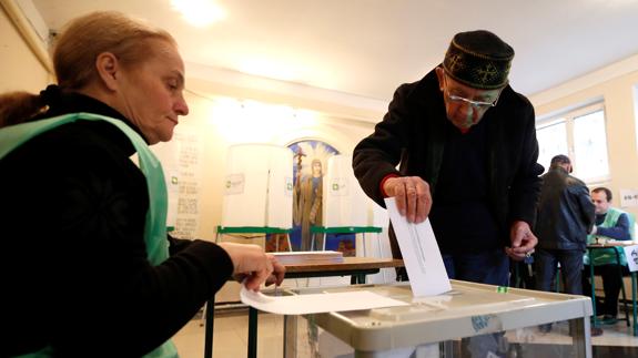 Un hombre deposita su voto.