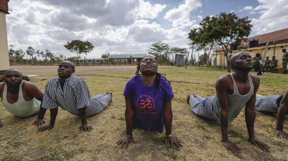 La instructora Irene Auma (c) da clases de yoga a prisioneros en la cárcel Athi River en Kitengela, a las afueras de Nairobi (Kenia).
