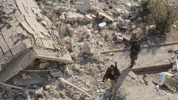 Soldados sirios caminan entre escombros en Alepo.