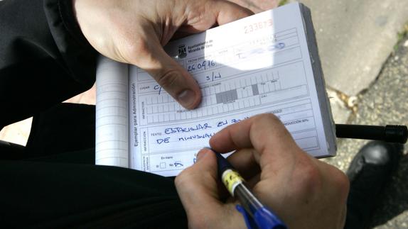 Un agente multa por mal estacionamiento.