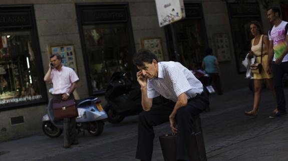 Dos hombres hablan a través de sus teléfonos móviles.