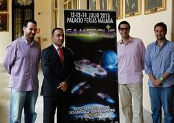 Los organizadores del evento posan delande del cartel de la feria. ::Sur
