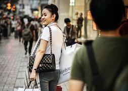 Una mujer chica cargada de bolsas de firmas de moda. ::Philippe Lopez/Afp