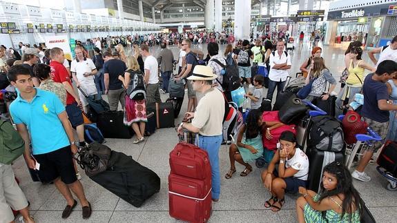 Turistas esperan en cola ante los mostradores de facturación del aeropuerto de Málaga.