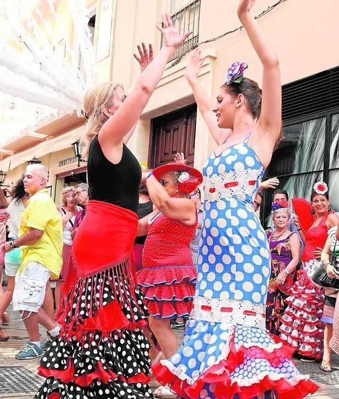 Dos mujeres bailan, vestidas de faralaes, en el Centro, donde la animación no cesa.